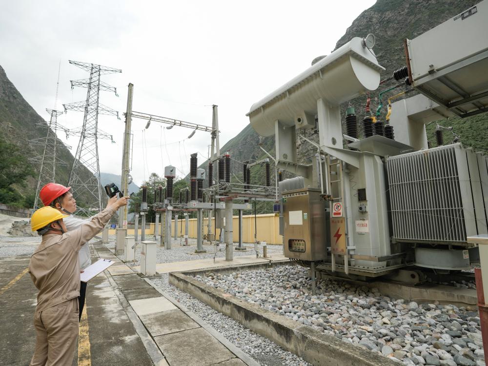 9月17日,在四川省汶川县灞州镇下庄水电站,国网四川岷江供电有限责任公司电力可靠性管理员朱鹏宇(后)和同事对升压站变压器进行例行测温。 新华社记者 王曦 摄