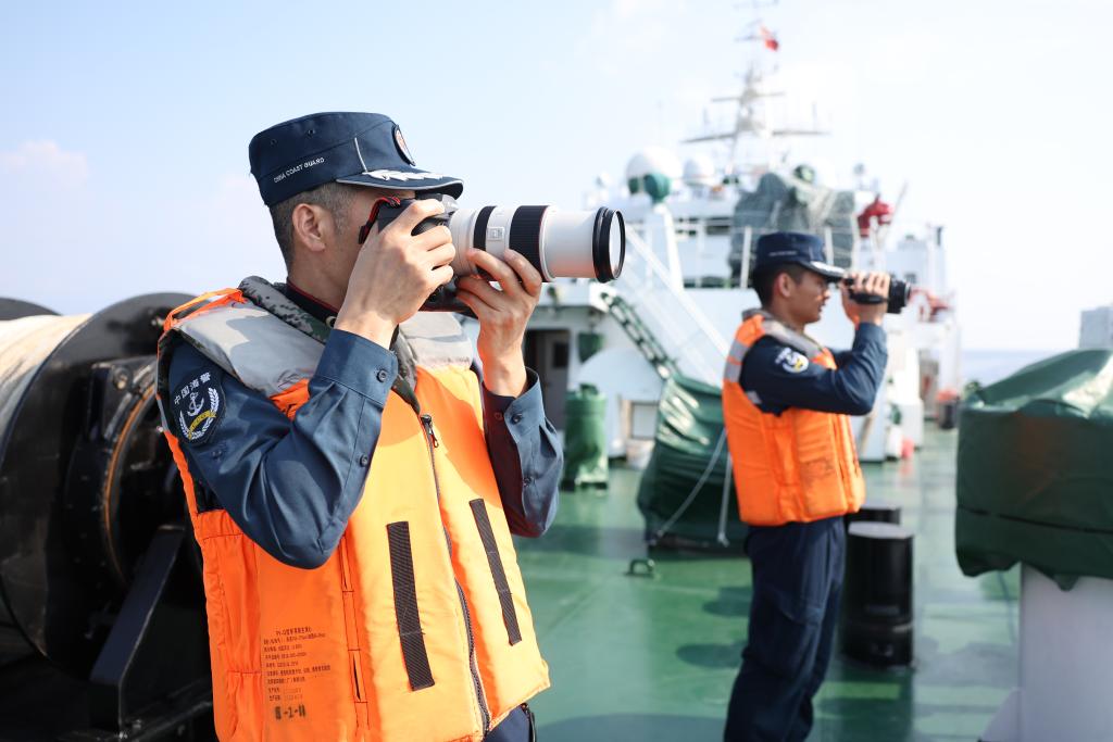 5月20日,海警执法员张继祥(左)在川山舰甲板上开展执法取证工作。新华社记者 陈斌 摄