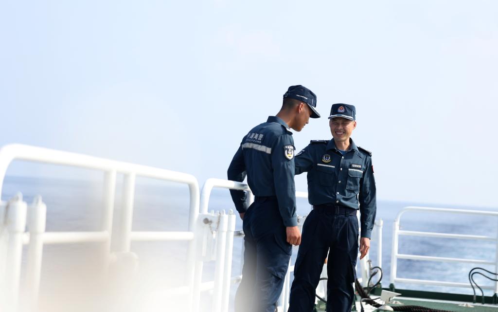 5月20日,海警执法员张继祥(右)和王鑫在川山舰甲板上交流。新华社记者 陈斌 摄