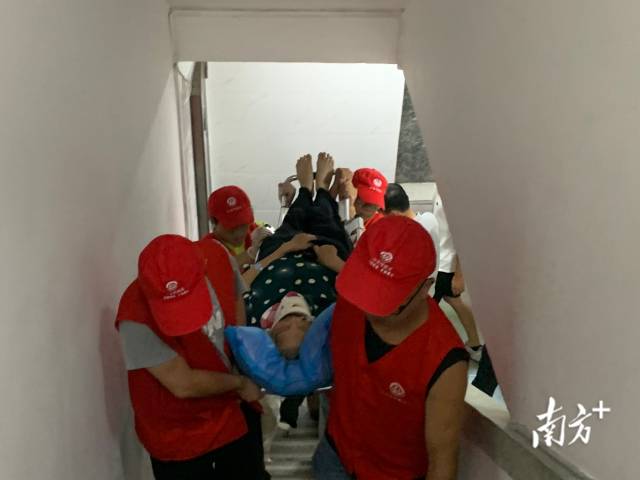 志愿者抬担架协助住院回家长者上8楼。 通讯员 供图